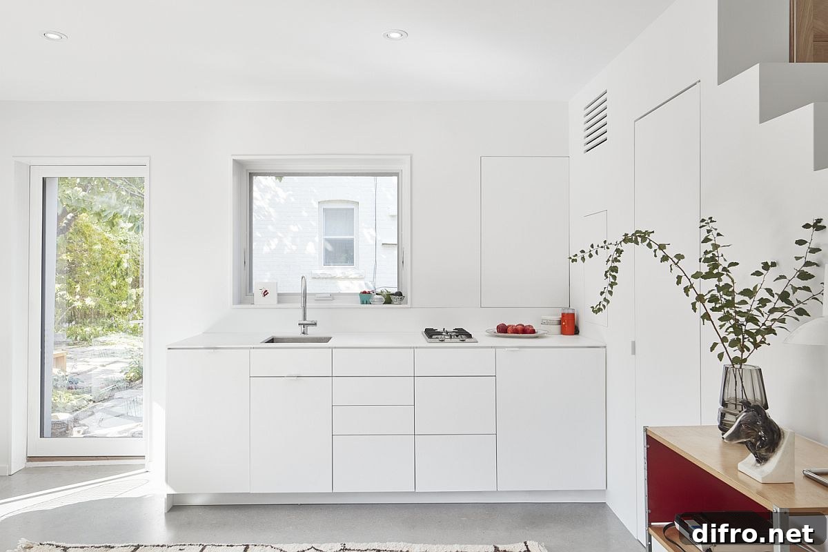 Modern, space-conscious kitchen in white inside small laneway house
