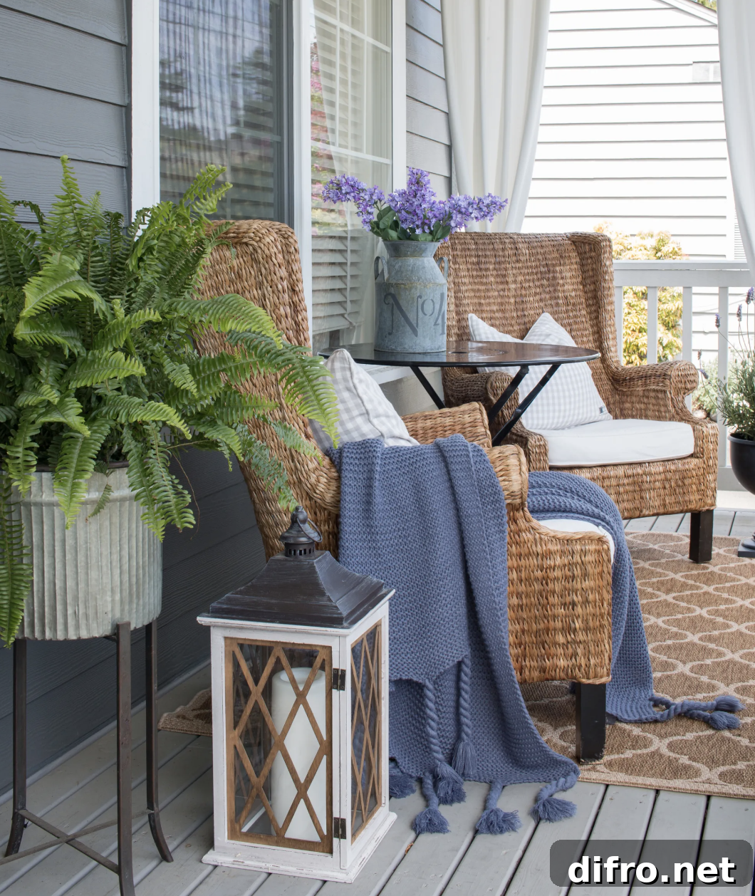 wicker armchairs on front porch with blue blanket throw metal tins flowers lanterns