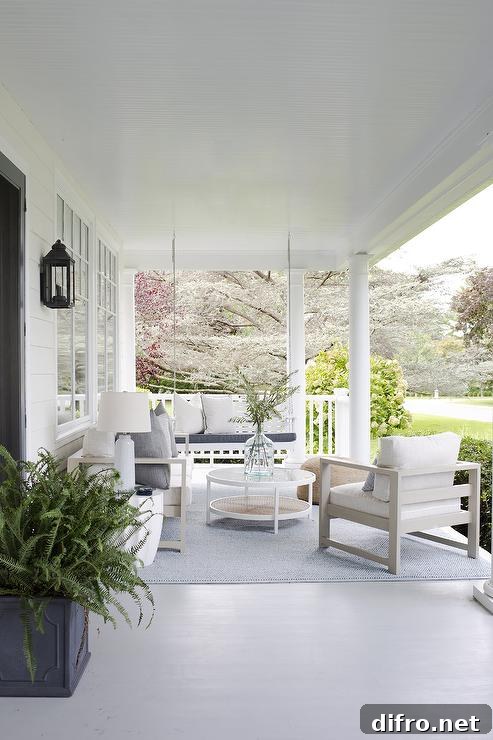 large view of front porch with white sitting chairs coffee table outdoor rug and fern in pot