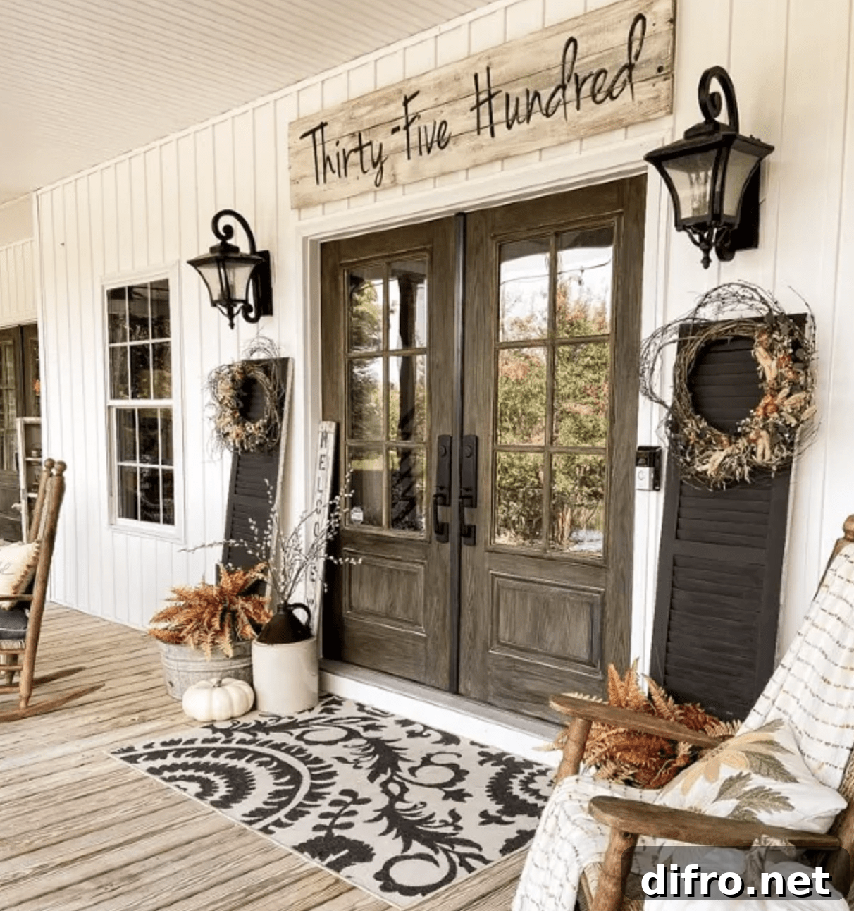front porch with double wood doors sign over top black lanterns and shutters with wreaths fall decorated