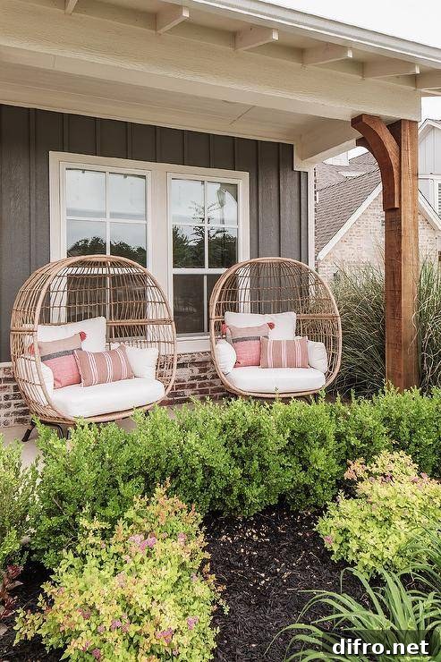 rattan chairs sit side-by-side on a covered front porch complementing a black cottage home