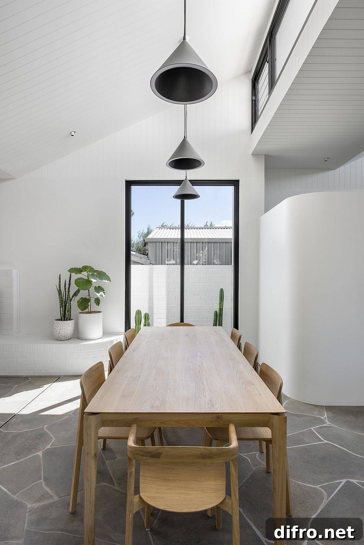 Dining area with sloped ceiling and black pendant lights