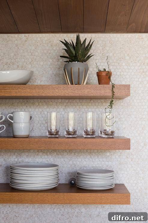 Brown floating shelves on white penny-tile backsplash.