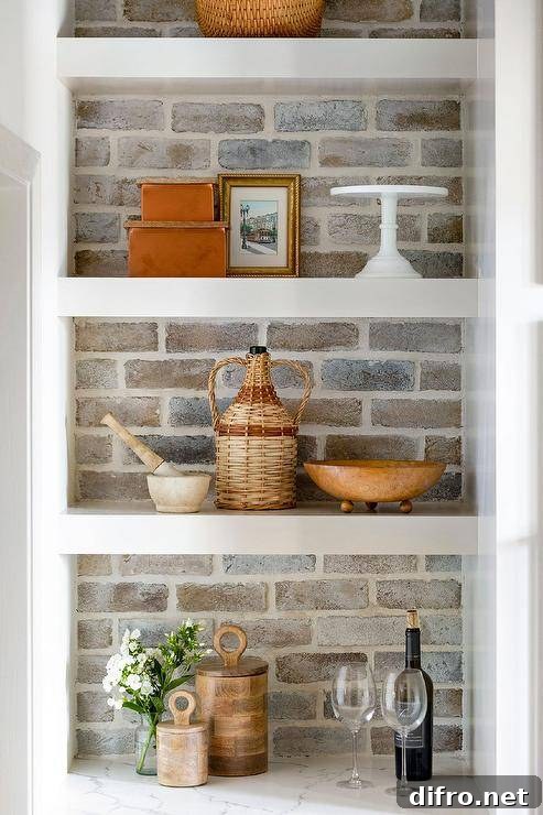 Cottage style kitchen finished with faded red brick backsplash, white shelves and styled decor.