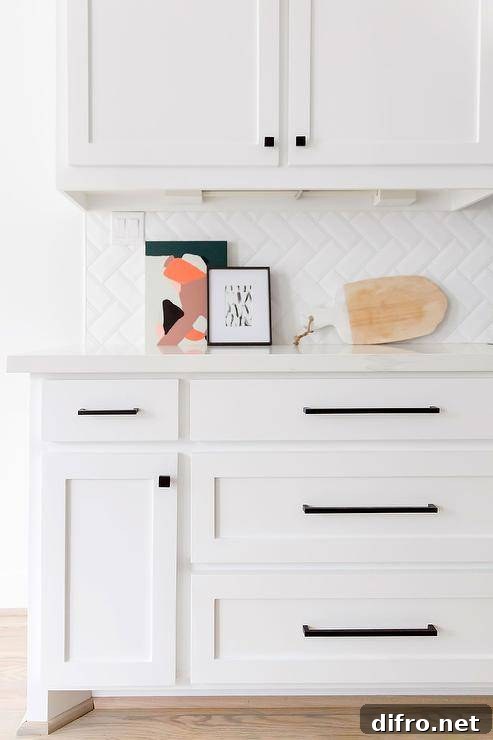 White kitchen with white herringbone backsplash tiles.