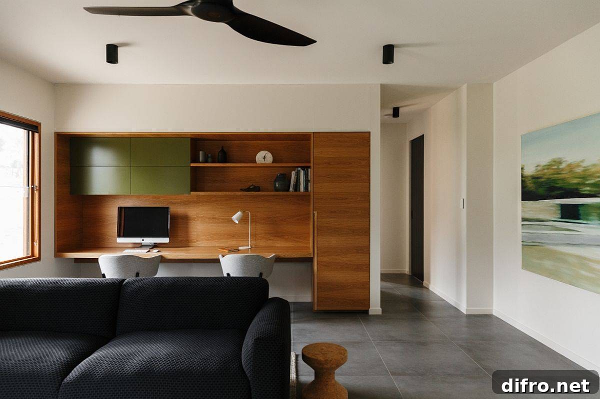 Custom home office design with a built-in wooden desk and comfy chairs