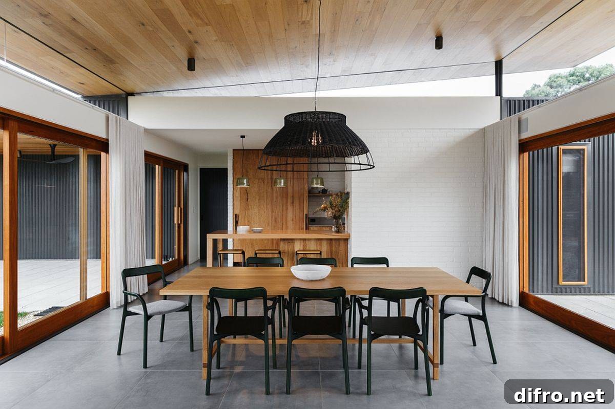 Modern dining room of the Aussie home with gray floor, sliding glass doors and wooden table