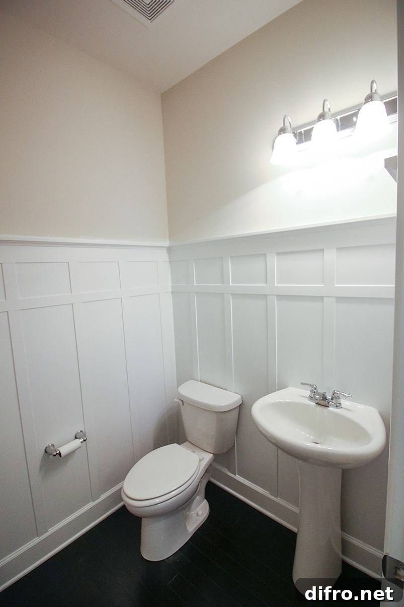 White toilet and white sink with white wall wainscoting