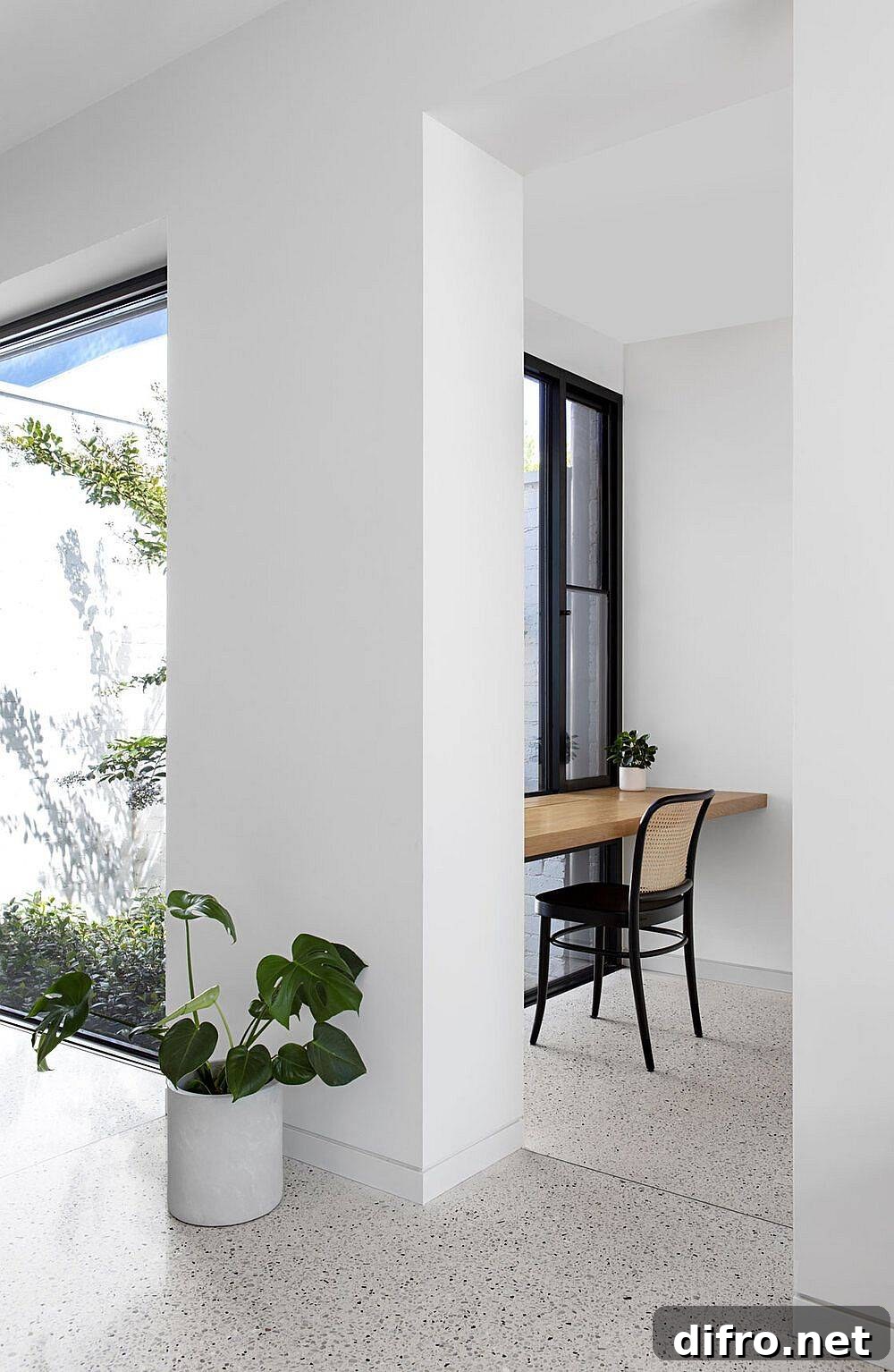 Slim floating wooden desks at the end of a long, open hallway with ample natural light serve as workstations
