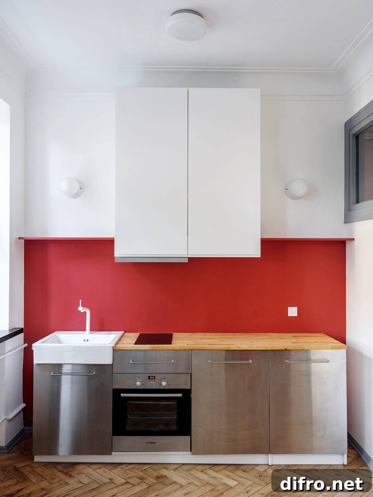 red wall in kitchen with stainless steel appliances and white cabinets