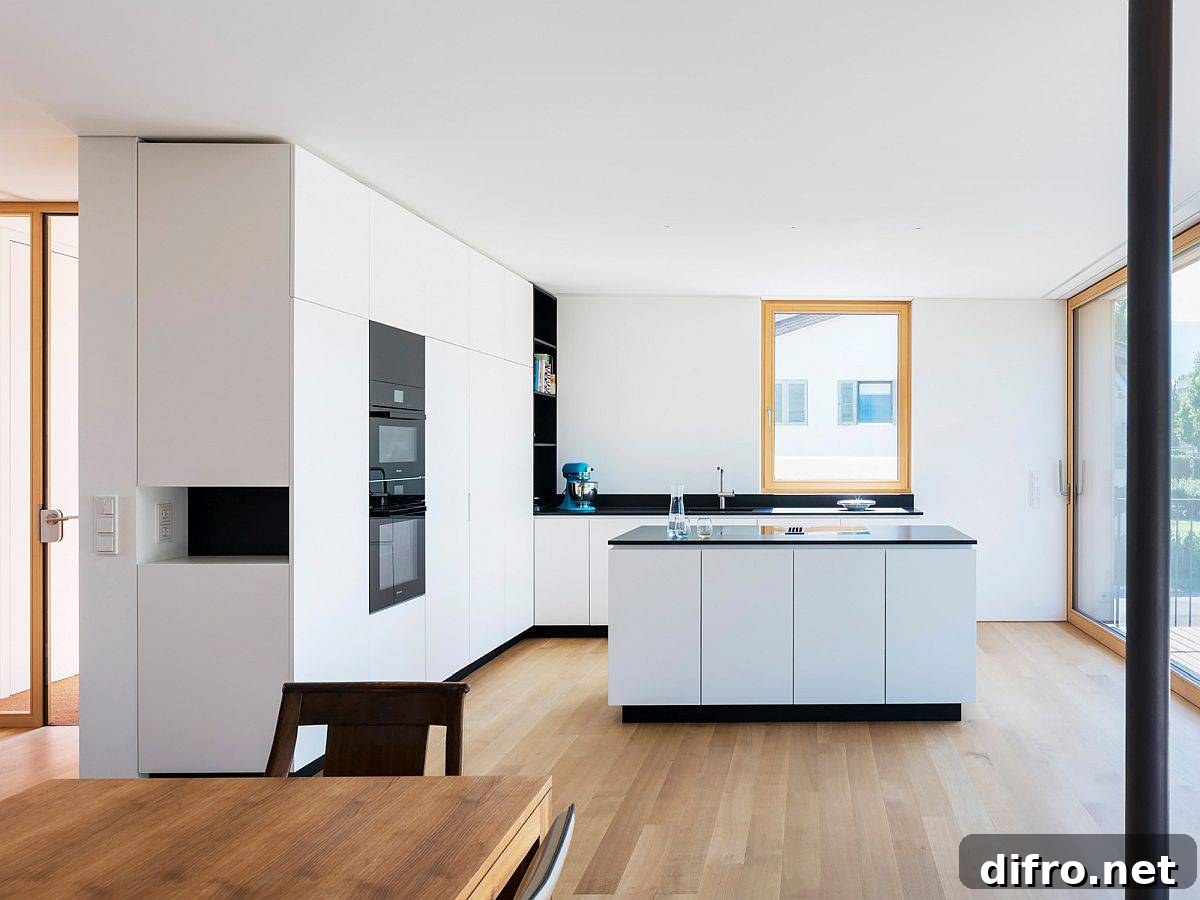 Sleek contemporary kitchen in white with wooden floors and appliances in black