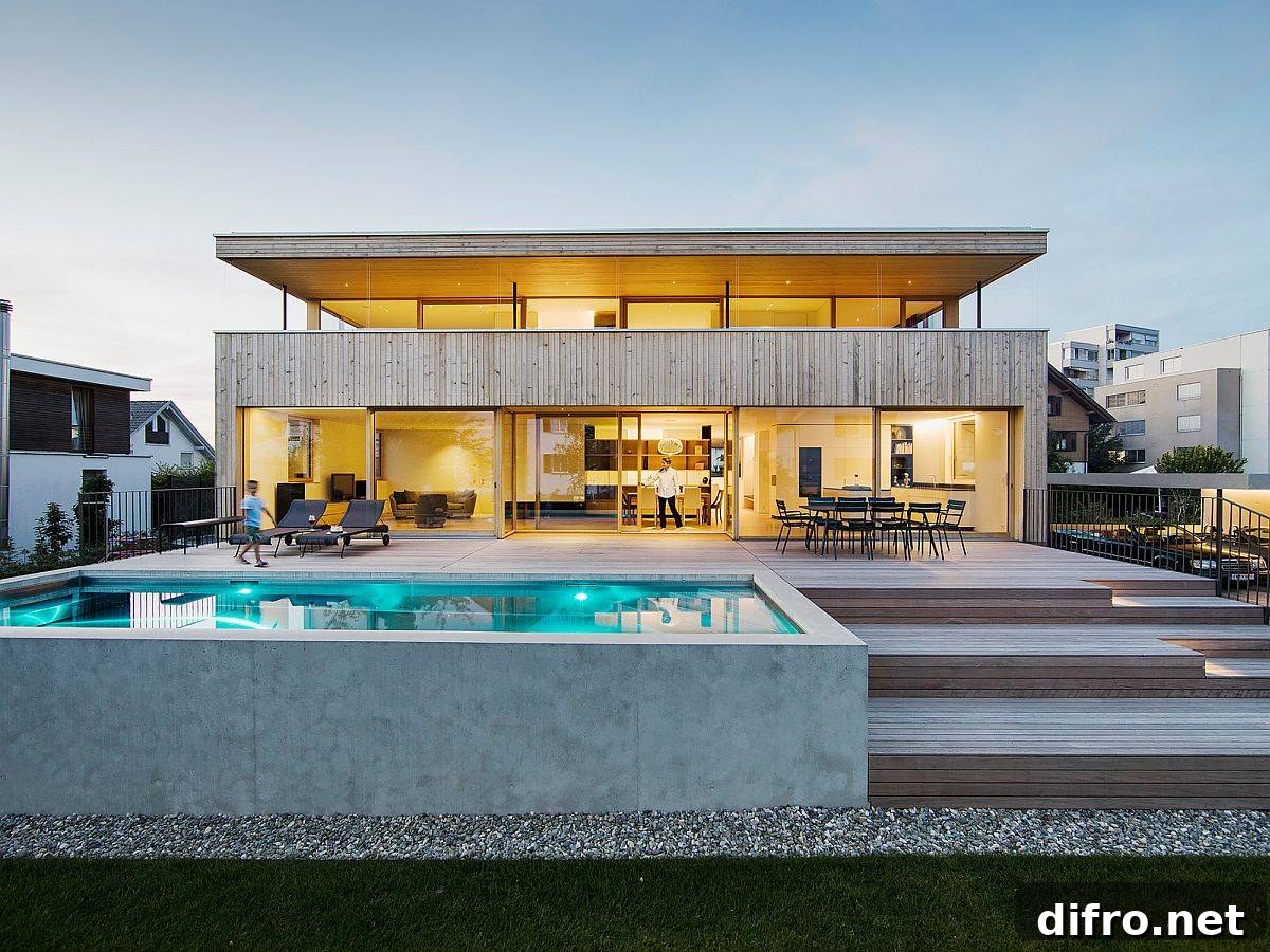 Warm lighting and floor-to-ceiling glass walls and sliding glass doors shape rear facade of the home