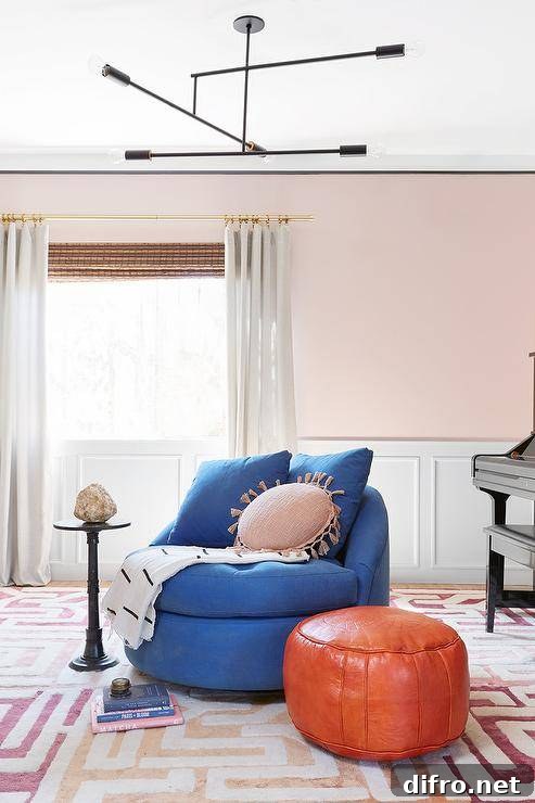 Elegant contemporary playroom is accented with blush pink walls lined with wainscoting and complementing white curtains hung from a brass rod in front of a bamboo roman shade.