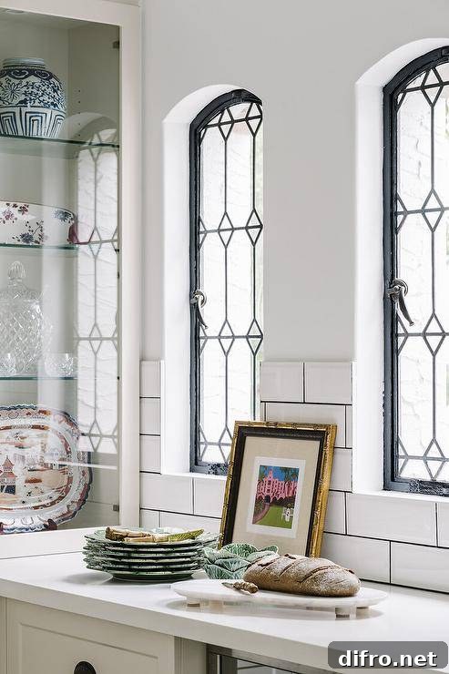Kitchen features arched leaded glass windows over a white countertop.