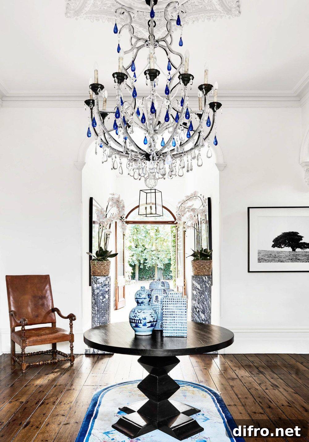 Entryway with a chandelier and a round hardwood table flanked by a chair.
