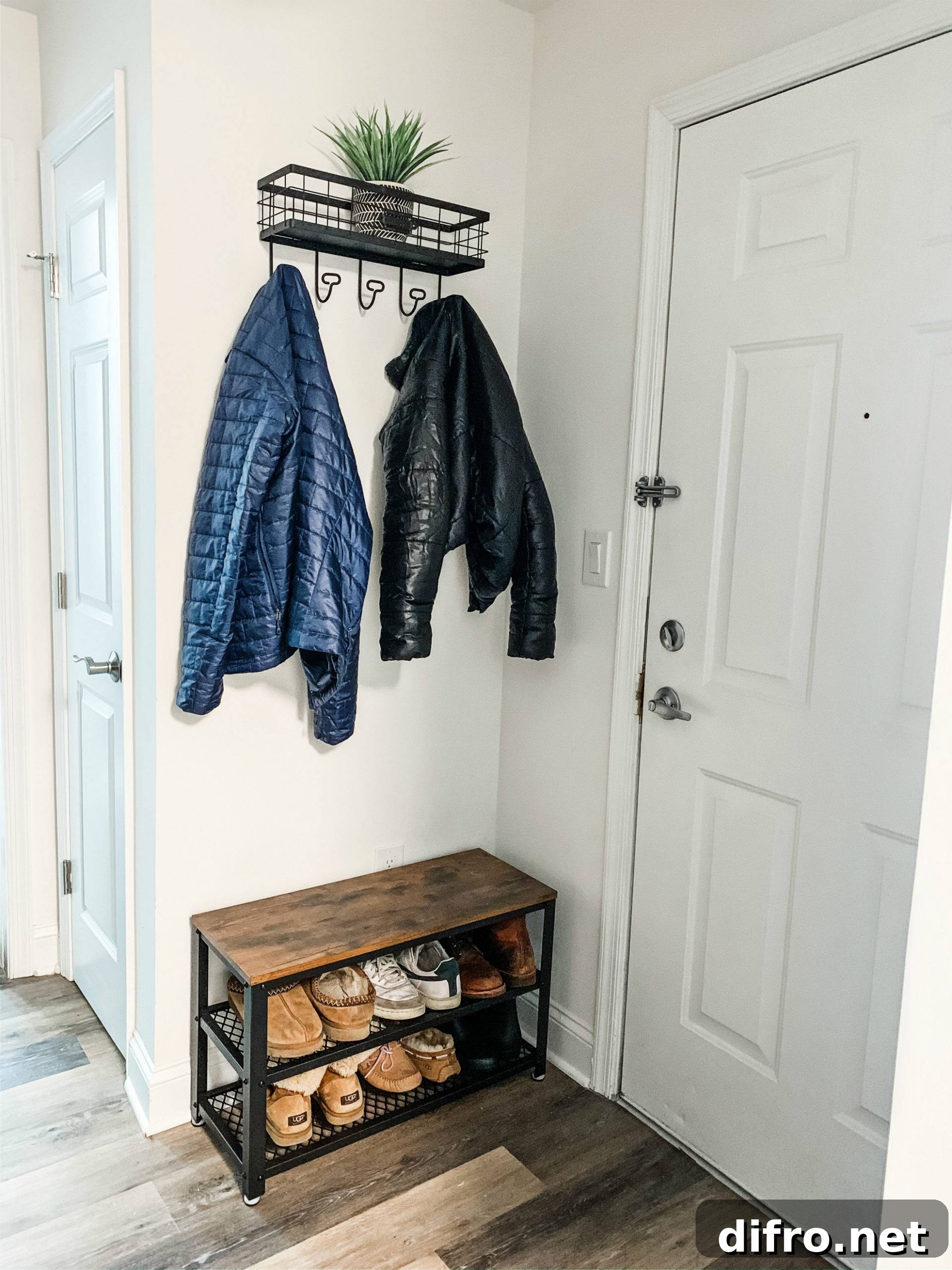 Entryway with a small bench that doubles as shoe storage with coat hung above it.