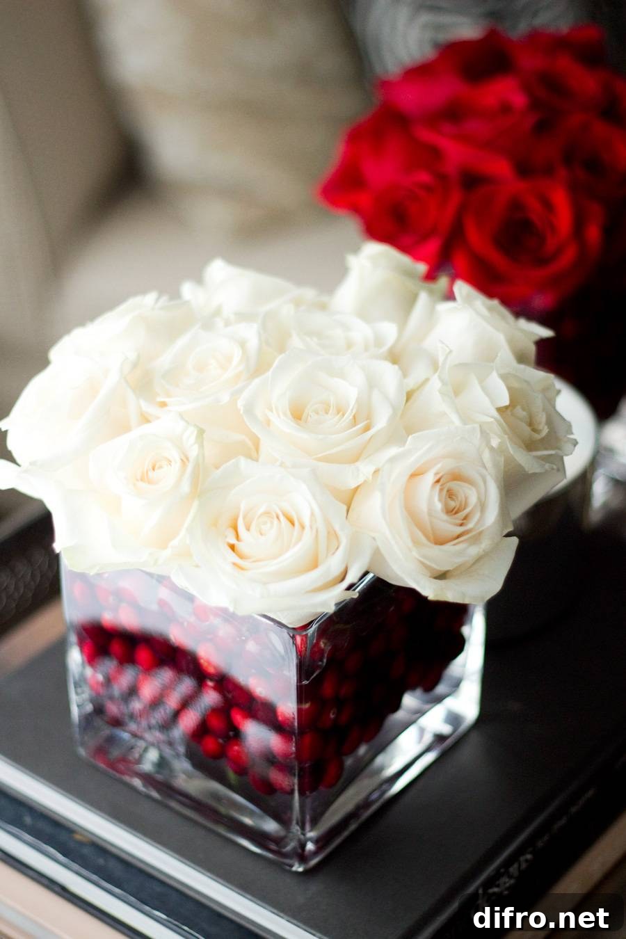 Glass vase filled with cranberries and white roses