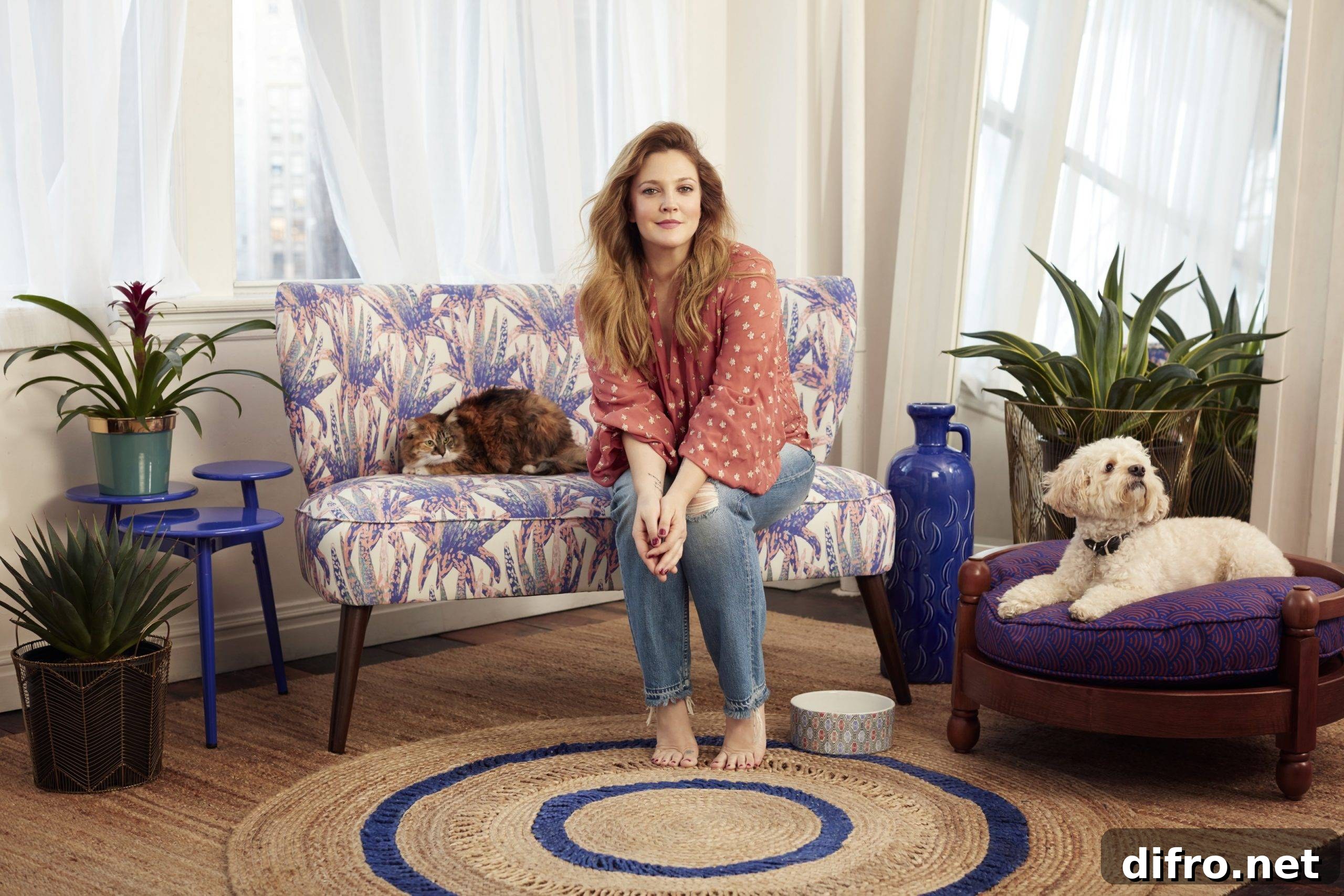 Drew barrymore sitting on a flower sofa with a cat and dog