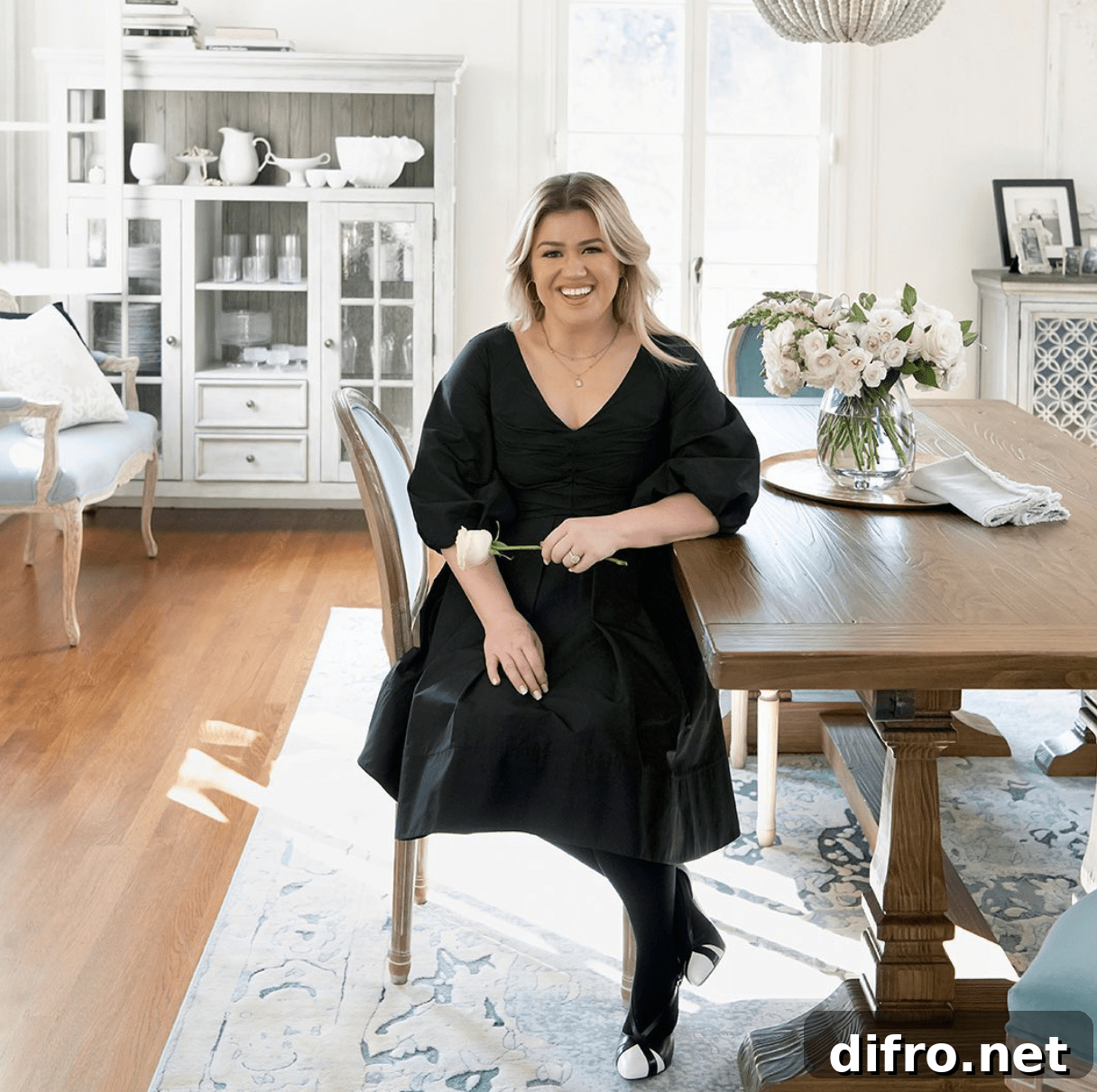kelly clarkson sitting at a table in a large decorated room