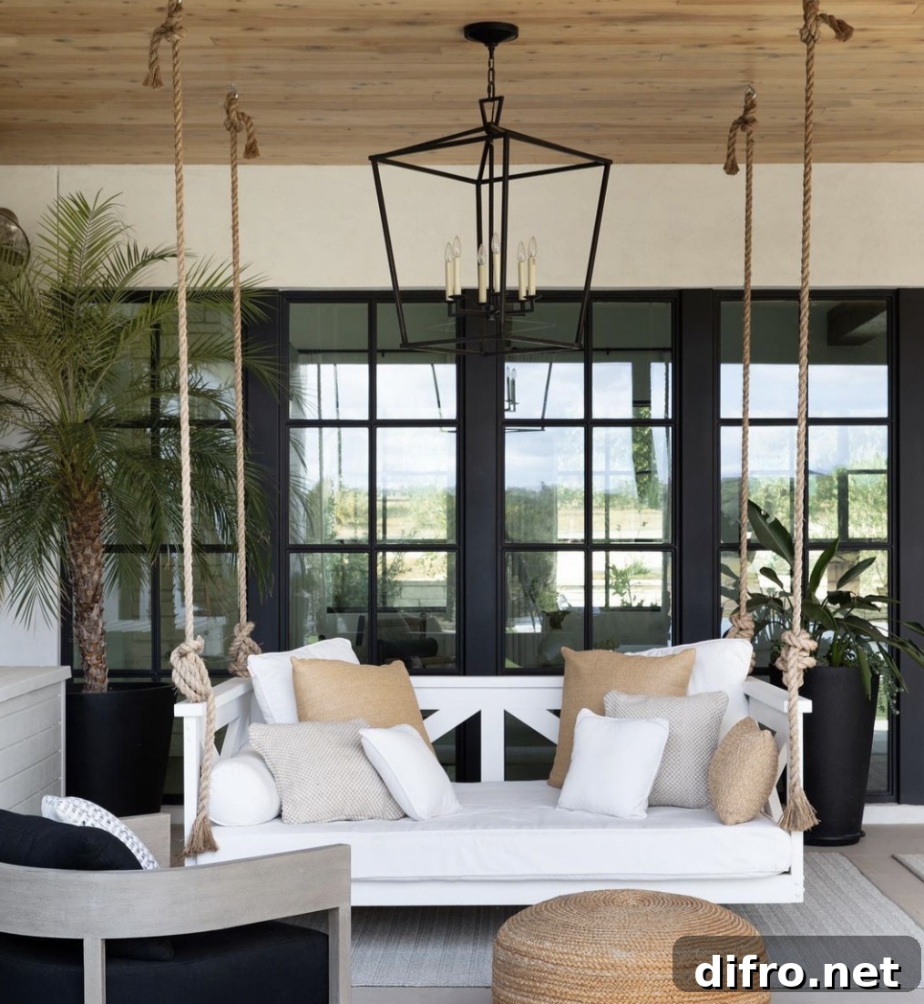 black hanging chandelier middle porch patio hanging bench swing white cushions frame windows wood ceiling