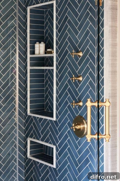 Blue tiled stacked shower niches are framed by blue herringbone shower wall tiles