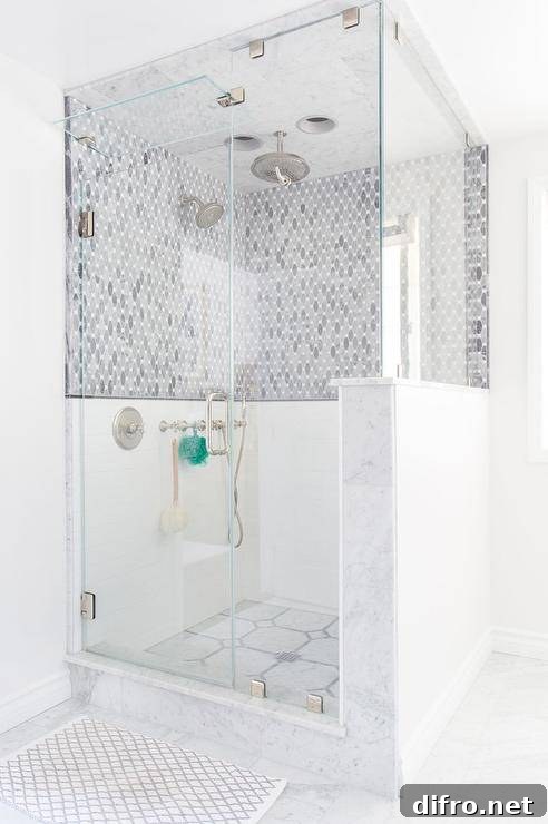 Walk in marble and glass steam shower with mosaic marble floors and a tiled niche
