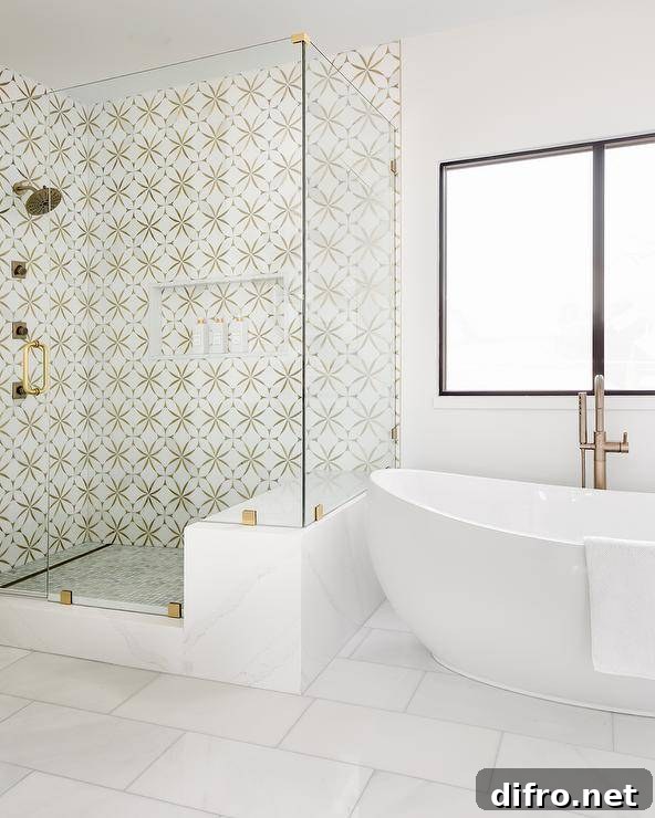 Seamless glass walk-in shower is clad in marble and brass mosaic surround tiles and is finished with a niche.