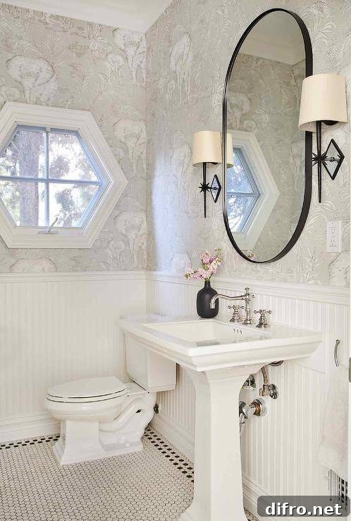 black frame oval mirror in half bath with pedestal sink wall sconces on either side toilet