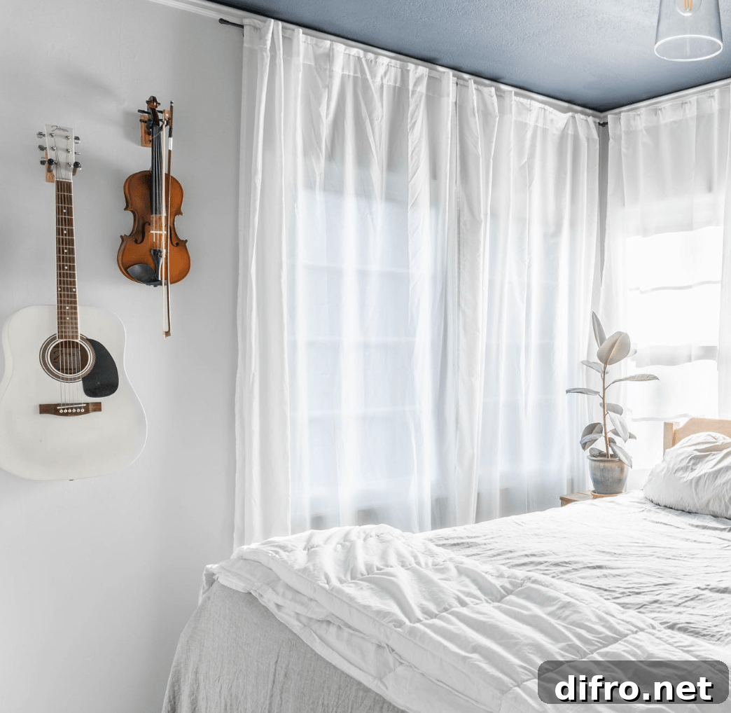 white bedroom with sheer curtains and white bedding with violin and guitar hanging on wall