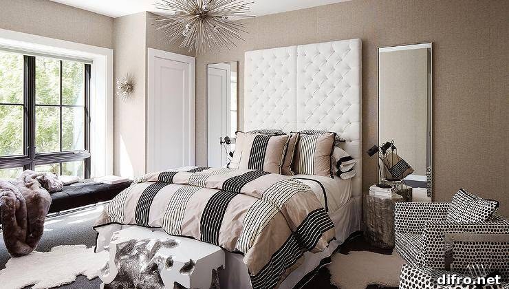 Full length mirrors are mounted against a light taupe wallpapered wall behind silver faux bois bedside tables and flanking side-by-side all white tufted headboards.