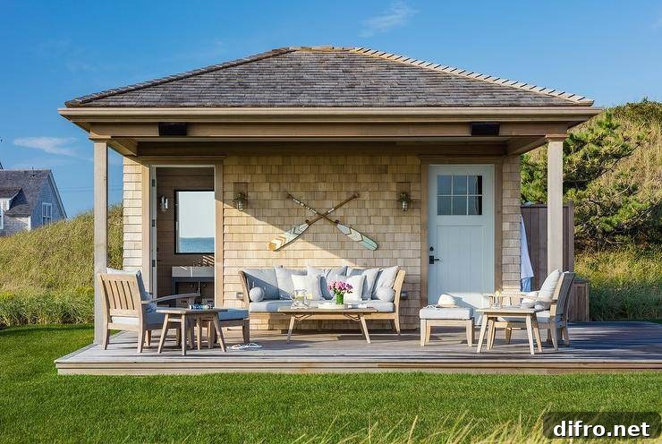 Relax on a cottage pool house deck with teak outdoor sofa, chairs and coffee table. Light brown shingles frame the deck displaying crossed canoe paddles.