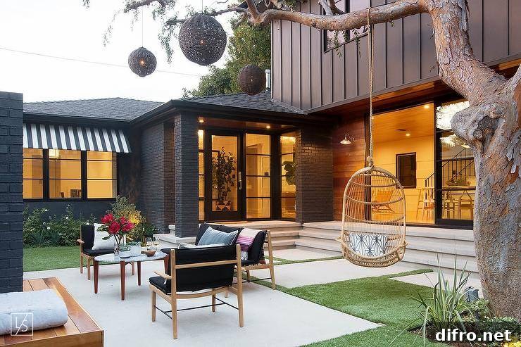 Contemporary sunken patio featuring a mature tree with a hanging woven chair and black woven chandeliers.