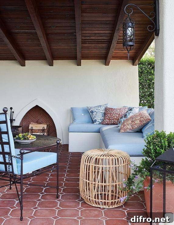Built-in l-shaped sofa on a covered patio with a blue cushion and Moroccan-style fireplace.