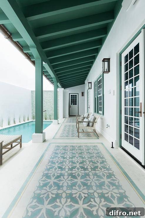 Long covered patio accented with green and aqua mosaic floor tiles under light gray chairs.