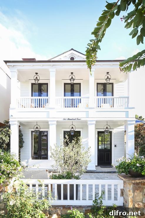 White two-story home with symmetrical carriage lanterns and black doors