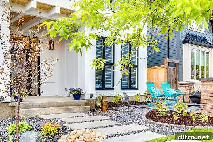 Concrete steps walk up to a covered porch while gravel surrounds the pathway along with plants, flowers, and accent stones.