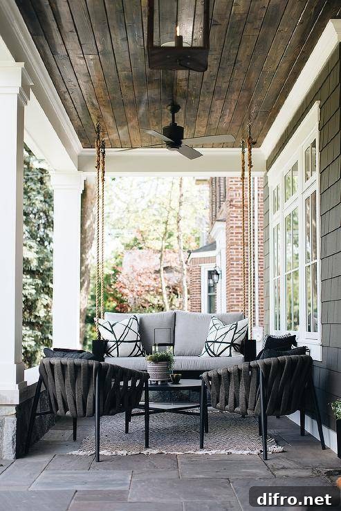 Kelly Wearstler Channels fabric on pillows on a gray outdoor black wooden porch swing.
