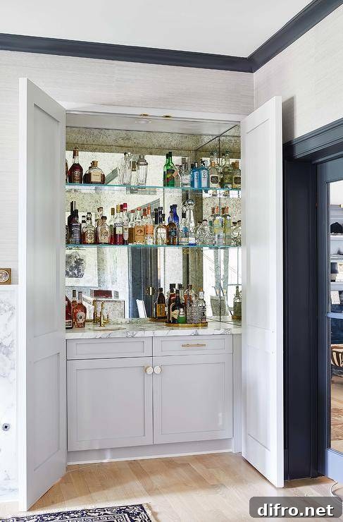 Hidden behind light gray double doors, glass shelves are mounted against a smoked mirror backsplash over light gray shaker cabinets.