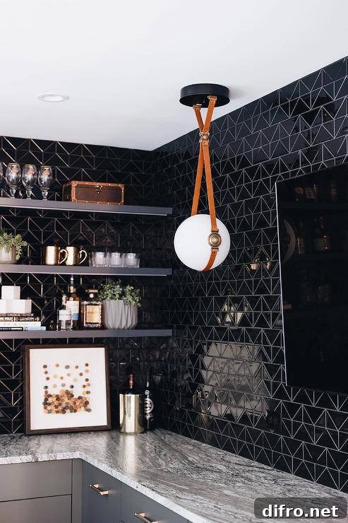 Contemporary wet bar features glossy black geometric tiles, black floating shelves and a flatscreen TV illuminated by a white glass and leather sphere pendant.