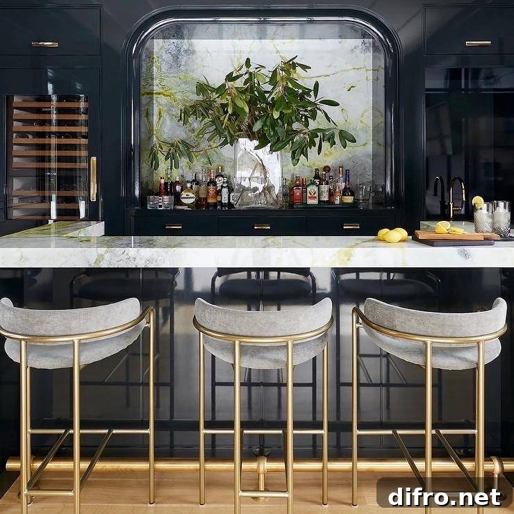 Chic home bar features gold and gray stools placed at a u-shaped glossy blue island topped with a marble countertop.