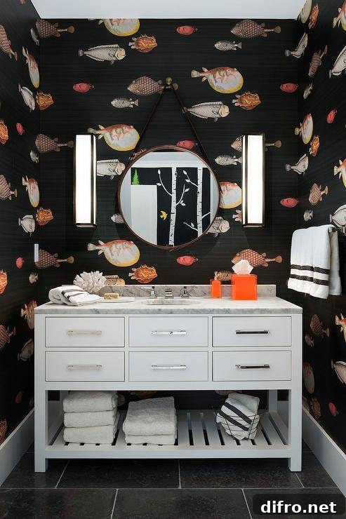 orange and black fish themed pattern wallpaper in a transitional bathroom with a Restoration Hardware Hutton Single Extra-Wide Washstand with a slatted shelf accented with polished nickel pulls. Carrera marble vanity top around the bathroom sink and nickel faucet are highlighted by a set of nickel and glass box sconces lighting up a unique and fun bathroom design.
