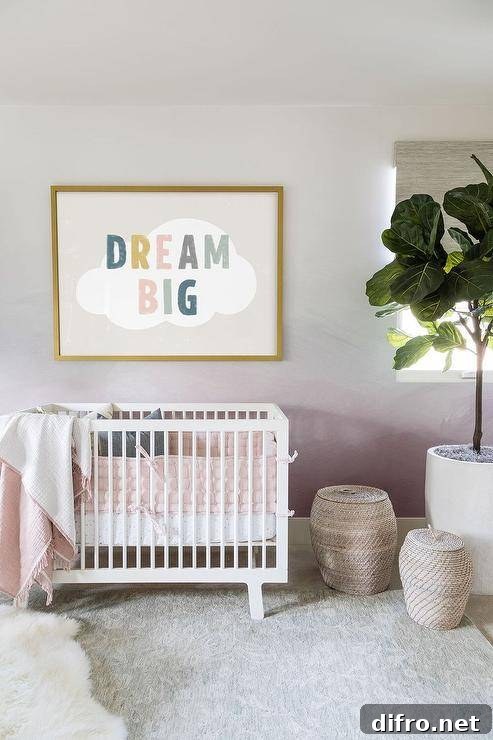 Nursery features Dream Big art on a pink ombre accent wall over a white Oeuf Sparrow crib and woven baskets on a light gray rug.