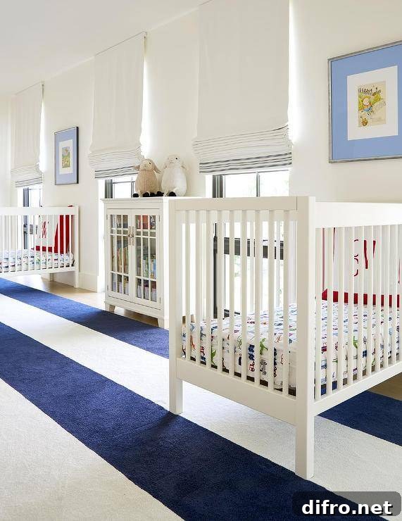 Spacious twin nursery design features a navy blue awning stripe rug, white wooden nursery cribs and a white glass front cabinet.