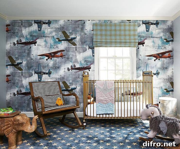 Nursery features Rebel Walls aero show wallpaper with vintage airplanes, a vintage black and white stripe nursery rocker, a brass crib, a gray rocking horse, a wooden elephant accent table atop blue and gray stars nursery carpeting and a green plaid window shade.