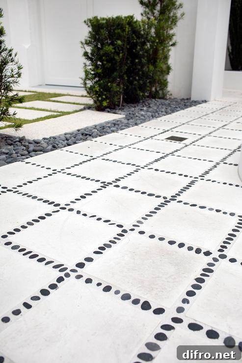 Patio features concrete pavers lined with black river rocks.