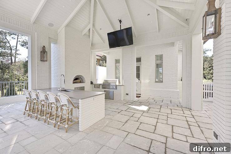 White French bistro stools at a concrete top island in a spacious covered patio with a white brick outdoor kitchen.