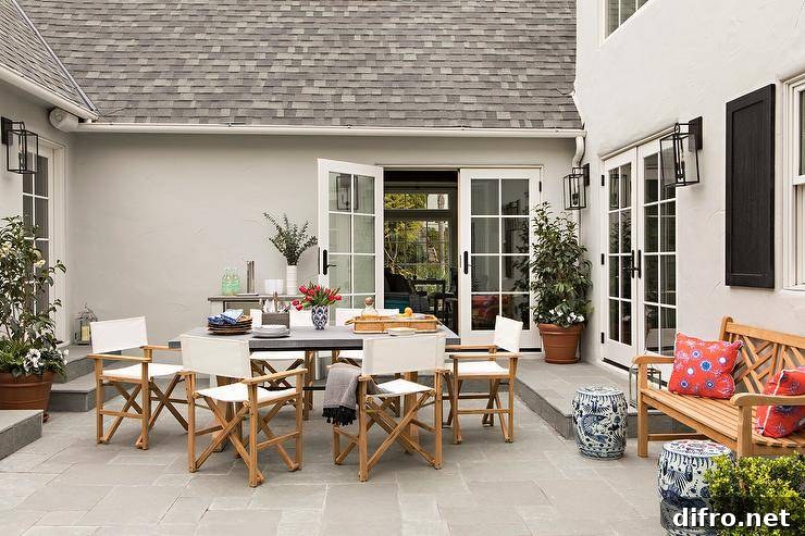 Ivory director's chairs on slate pavers around a concrete patio dining table.