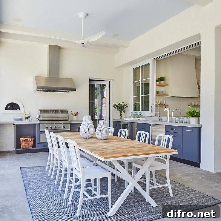 Covered patio dining space fitted with a teak plank top table placed on a concrete floor covered in a blue rug.