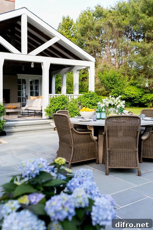 Slate patio paver floors showcasing a concrete dining table in front of a cottage.
