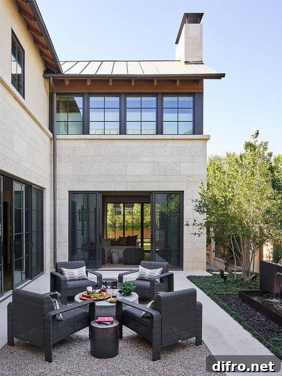 Black wicker lounge chairs sit around a round concrete coffee table placed on a gravel patio.